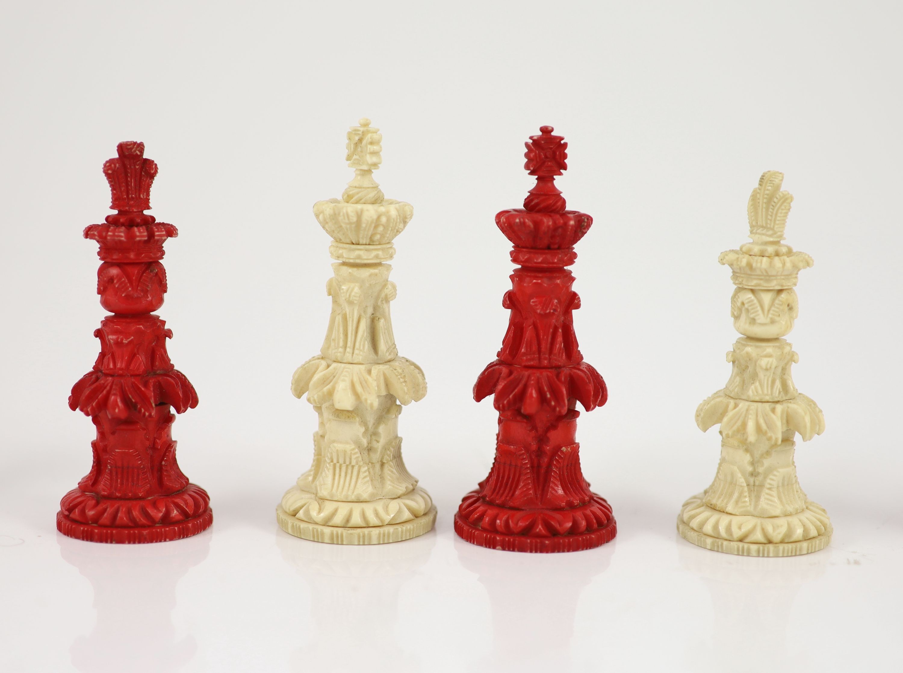 A 19th century Anglo-Indian white and stained bone chess set, with unusual carved palmate decoration, Kings 9.5cm.